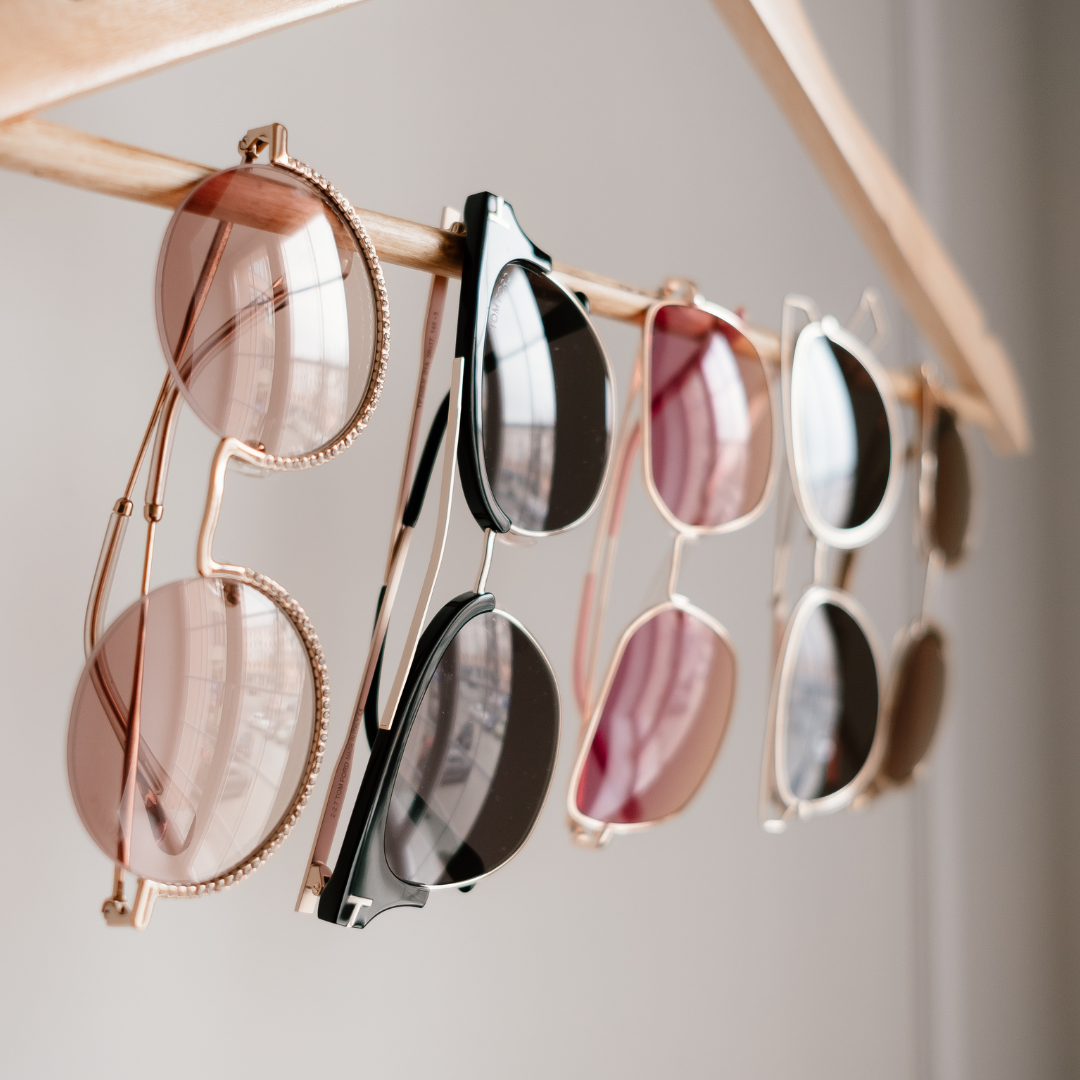 5 pairs of sunglasses hanging on a bar